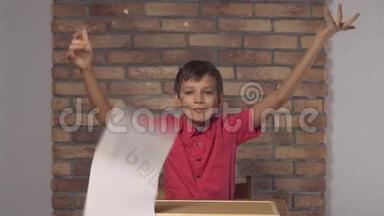 坐在书桌前的孩子拿着一张在背景红砖墙上刻有自由字母的挂图